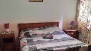 Un dormitorio con una cama de madera, un cuadro floral en la pared, una lámpara de noche y una mesita de noche.