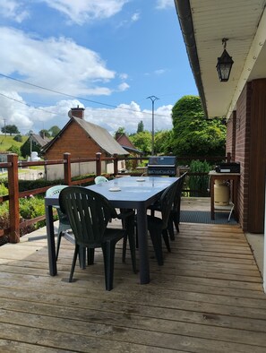 Eine Terrassenausstattung mit Tisch, Stühlen, einem Grill und einem Warmwasserbereiter.