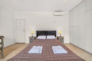 Ein Schlafzimmer mit einem Bett, zwei Nachttischen mit Lampen, einem Kleiderschrank und einer Klimaanlage.