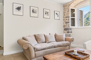 Ein Wohnzimmer mit einem beigefarbenen Sofa, einem Couchtisch und vier gerahmten Pflanzenbildern an der Wand.