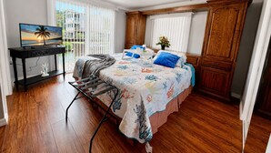 Une chambre à coucher avec un lit, un bureau, une télévision et une vue sur l’extérieur.