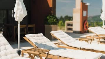 Una terrazza con lettini, un tavolo e ombrelloni.