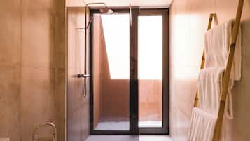 Ein modernes Badezimmer mit Duschkabine aus Glas, einem Handtuchhalter und einem sichtbaren Fenster.