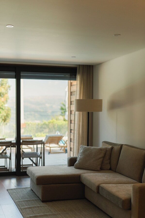 A modern living room with a sectional sofa, a lamp, and a view of outdoor seating.