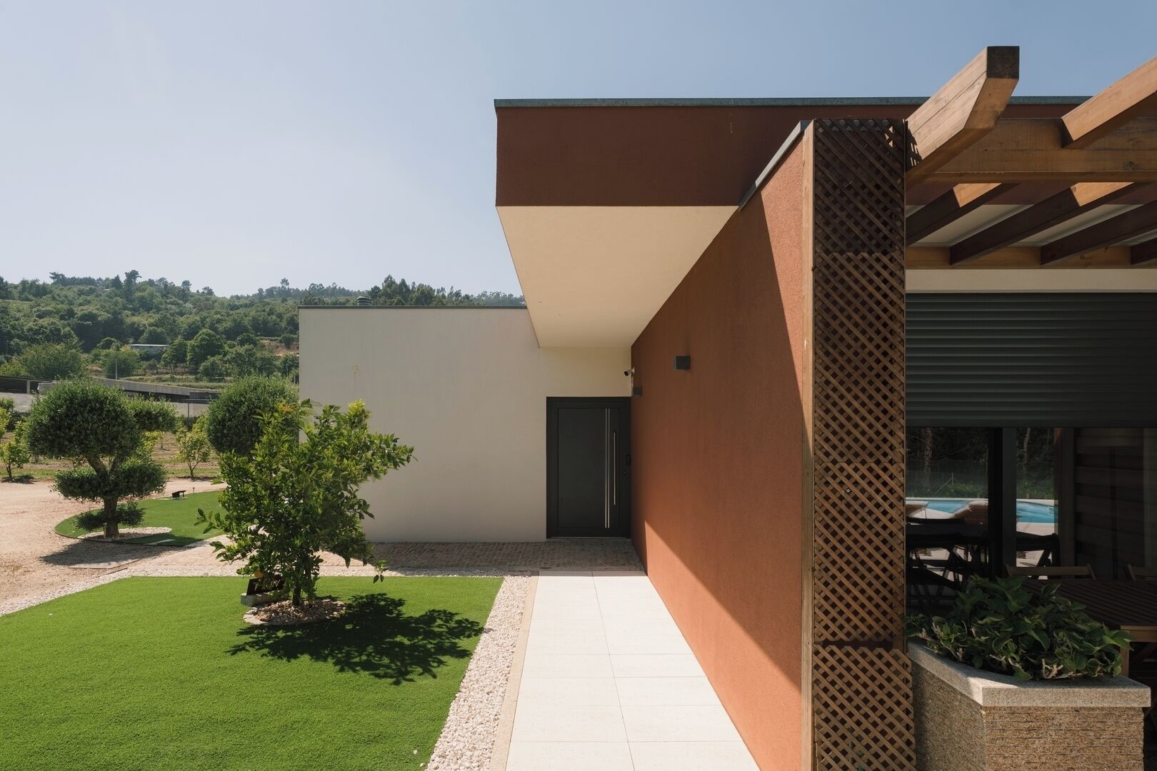 Un bâtiment moderne doté d’un toit plat, sous un ciel dégagé, et d’une pelouse bien entretenue agrémentée d’arbres.