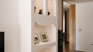 Un intérieur moderne avec un mur blanc incurvé, un plancher en bois et un téléviseur placé à gauche.