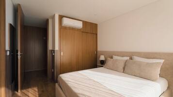 A bedroom with a bed, wooden wardrobe, and an air conditioning unit.