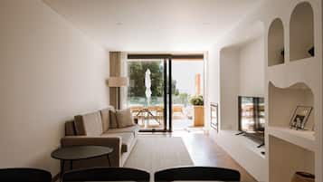 Una sala de estar moderna con un sofá, una mesa de centro, televisor y un balcón con mobiliario exterior.