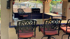 Un patio exterior con una parrilla, asientos y un respuesto de azulejos.