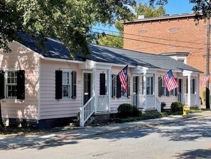 Ein pinkfarbenes Haus mit schwarzen Fensterläden, einer Veranda und amerikanischen Flaggen.