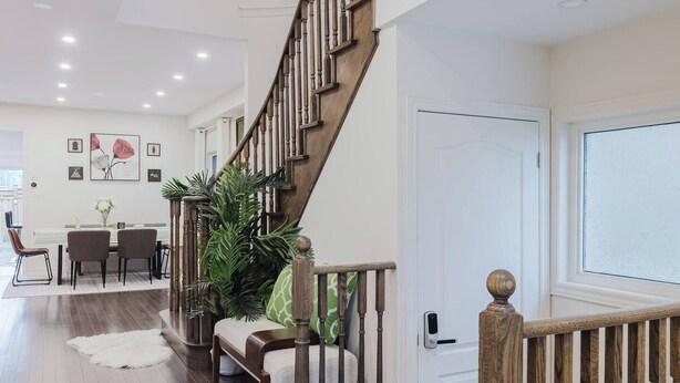 A staircase with wooden balusters, a dining area with a white tablecloth, and a large potted plant.