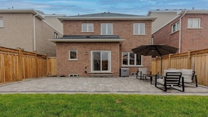 A brick house with a patio, a wooden fence, and outdoor furniture.
