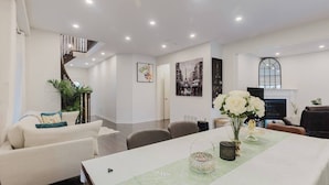 A modern living room with a sofa, dining table, and a fireplace.
