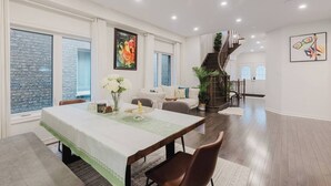 A spacious living area with a dining table, a staircase, and a large window. - Spacious 4BR Retreat | Backyard | Near Ontario (Oshawa)