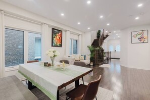 A spacious living area with a dining table, a staircase, and a large window. - Spacious 4BR Retreat | Backyard | Near Ontario (Oshawa)
