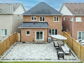 Ein Garten mit Terrasse, Sitzgelegenheit und Holzzaun.