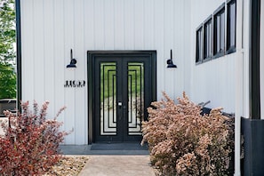 A modern building with a black double door, two wall-mounted lights, and a number '11059' on the door. - The Factory House at Keuka Lake: Hot Tub, BBQ, Unreal Lake Views, Chef's Kitchen (Hammondsport)