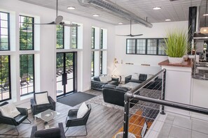 A spacious living area with large windows, a modern kitchen, and a staircase. - The Factory House at Keuka Lake: Hot Tub, BBQ, Unreal Lake Views, Chef's Kitchen (Hammondsport)