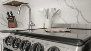 Une cuisine équipée d’une cuisinière, d’un bloc à couteaux et d’un mur au motif de marbre.