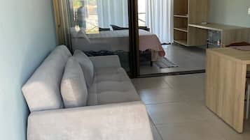 Una sala de estar moderna con un sofá, una mesita y un puerta corredera que da a un dormitorio.