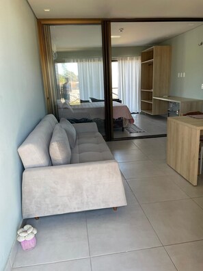 Una sala de estar moderna con un sofá, una mesita y un puerta corredera que da a un dormitorio.