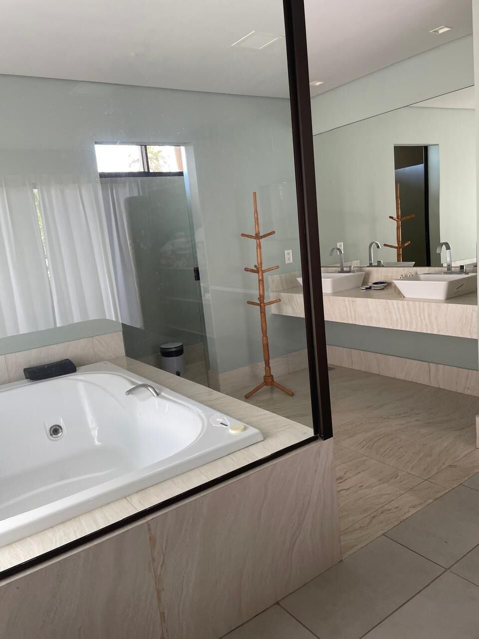 A modern bathroom with a large mirror, a bathtub, and two sinks.