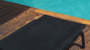 A wooden deck with a black lounge chair.