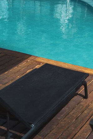 A wooden deck with a black lounge chair. - Villas BobZ (Cajueiro da Praia)