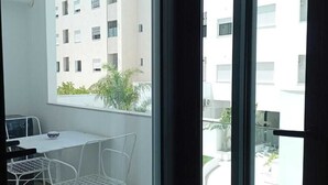 A balcony with a table and chairs, a view of a building, and a window. - sandra 12 (la soukra)