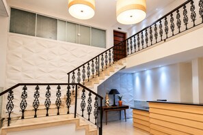 Ein modernes Interieur mit Treppe, Rezeption und einem geometrischen Wanddesign.