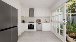 A modern kitchen with white cabinets, a stainless steel refrigerator, a dishwasher, and a gas stove. - Edenbrook in Prahran (Prahran)