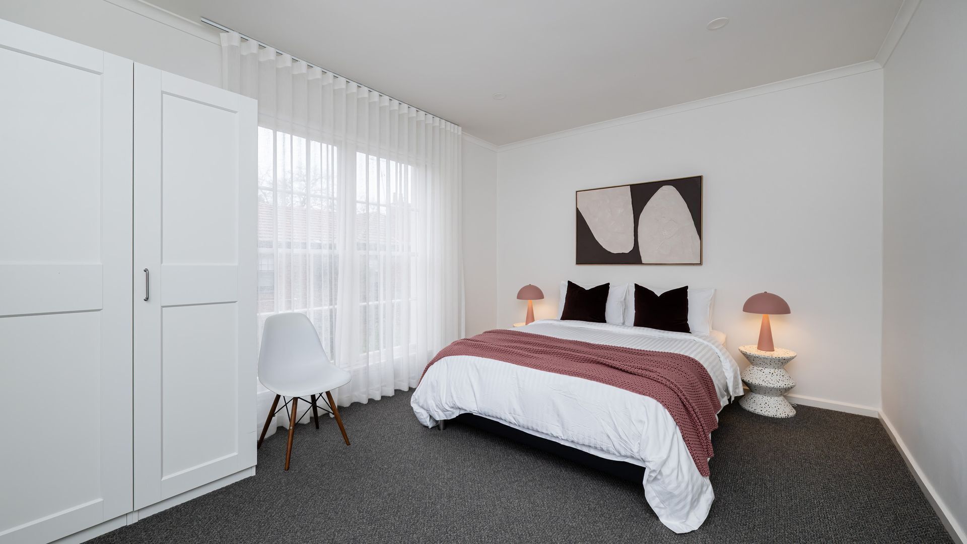 A bedroom with a bed, a chair, a desk, and a lamp.