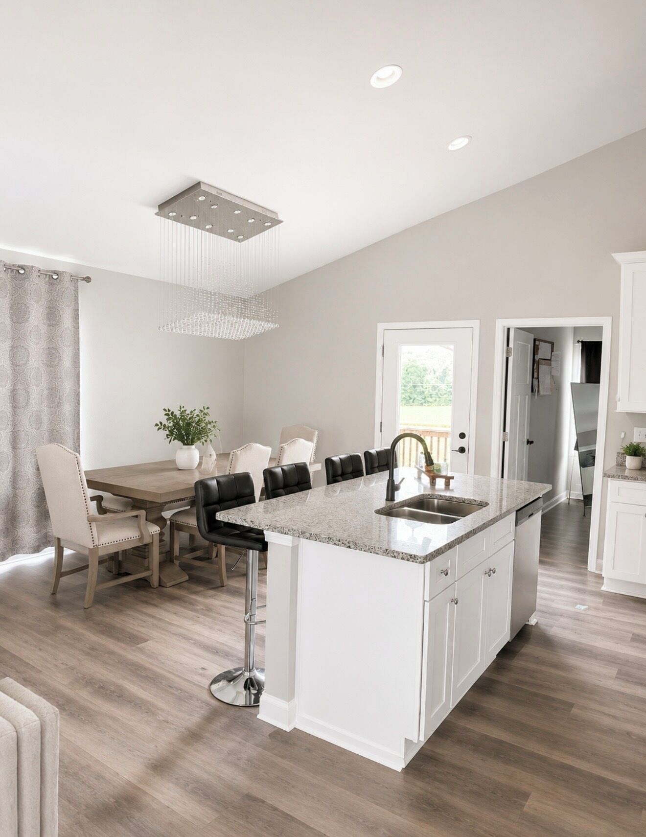 Une cuisine moderne dotée d’un îlot central, de meubles blancs et d’un coin repas avec une table et des chaises.