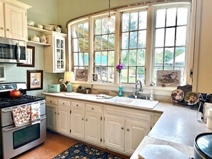 A kitchen with a stove, oven, sink, and large windows. - Spacious 6-bedroom house in tranquil Tracy City with AC (Tracy City)