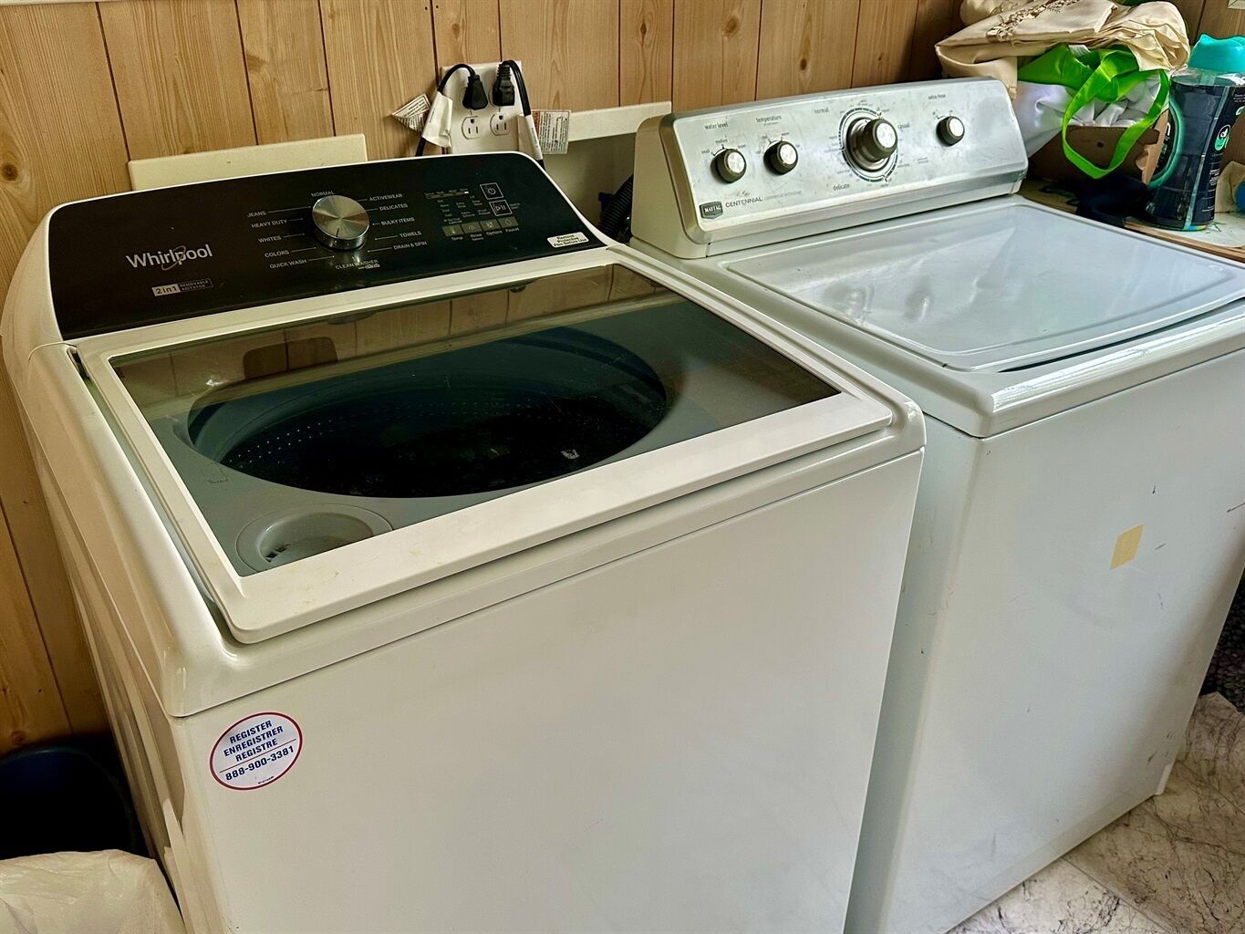 Eine Whirlpool Waschmaschine und ein Trockner in einem Waschraum mit Holzwänden.
