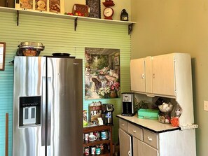 Eine Küche mit einem Edelstahlkühlschrank, einer Kaffeemaschine und einem Regal mit verschiedenen Gegenständen.