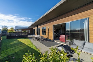 A modern house with a patio, a dining area, and a large sliding glass door leading to an interior space.