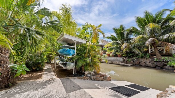 A water slide leading to a pool surrounded by tropical vegetation. - Fare Mahana (Tiahura)