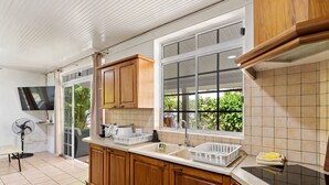 A kitchen with wooden cabinets, a large window, a sink, and a built-in stove.