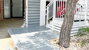 A covered outdoor area with a wooden deck, a metal railing, and a tree. - Ocean Block 3BR 2BA | Walk to Beach | Sleeps 8 (Ocean City)
