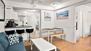A compact living space with a kitchenette, a dining area, and a sofa with a patterned pillow. - Ocean Block 3BR 2BA | Walk to Beach | Sleeps 8 (Ocean City)