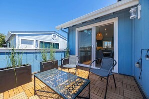 A patio with a glass table and chairs, a pool, and a building with a sliding glass door. - Harbor Home - Walking Distance to Twin Lakes Beach! (Santa Cruz)