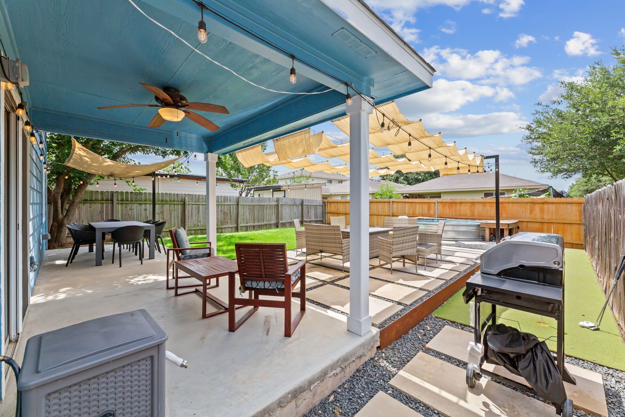 An outdoor patio with a ceiling fan, string lights, and a grill.