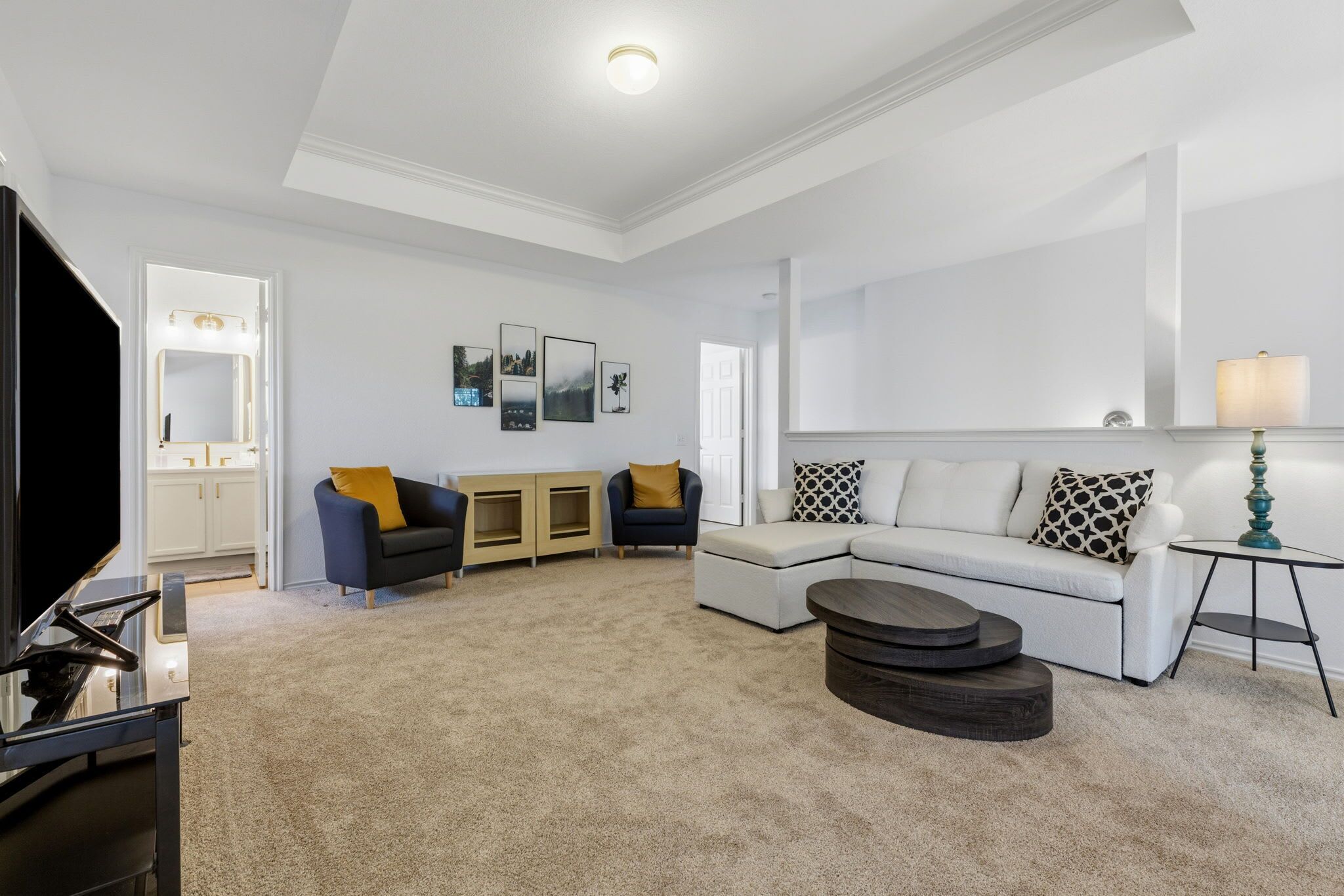 A living room with a sectional sofa, a TV, a coffee table, and a lamp.