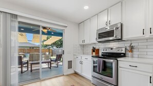 Una cocina moderna con armarios blancos, un horno de acero inoxidable y un microondas.