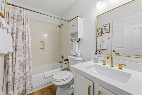 A bathroom with a shower, toilet, sink, and cabinet.