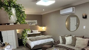 Ein modernes Hotelzimmer mit Bett, Sofa, rundem Couchtisch und Schreibtisch mit Lampe.