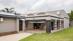 Ein modernes Haus mit einer überdachten Terrasse, einer Satellitenschüssel und einer Ziegelwand.