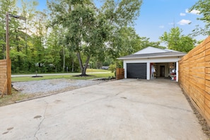 Eine Garage mit Holzzaun, Auffahrt und Bäumen im Hintergrund.