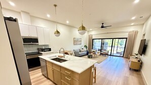 A modern kitchen with a central island, built-in appliances, and a dining area with a sofa and coffee table. - Sea Salt Cottages AC • Two Luxury Villas • Sleeps 12 next Boca grande Beach (Port Charlotte)